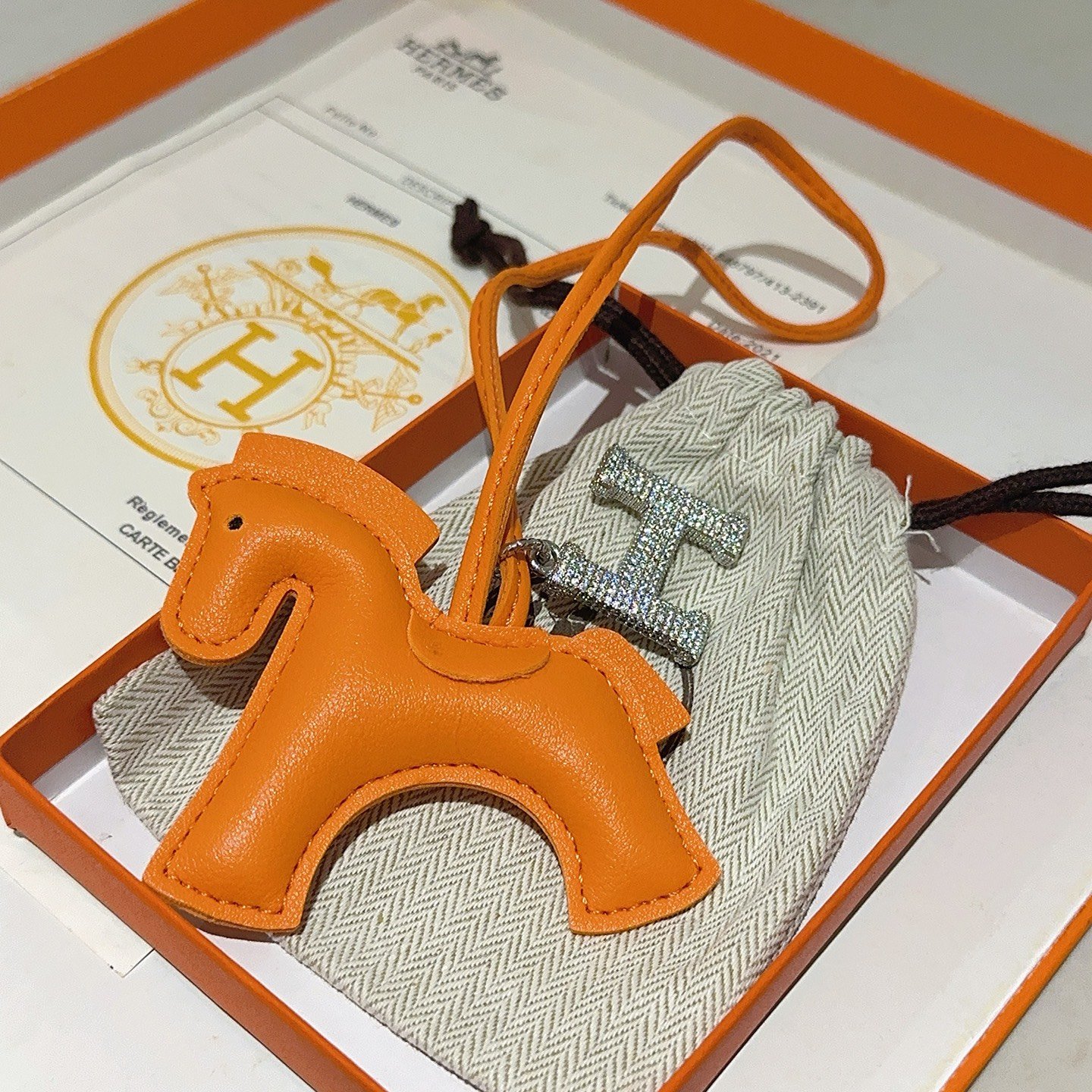 Ciondolo per borsa Hermes Rodeo Horse con pendente Pave H. Pelle arancione, metallo argentato con cristalli trasparenti, lunghezza del cinturino di 12 cm.